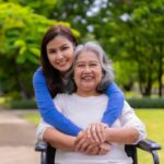 adult daughter hugging older mother who is sitting in a wheelchair