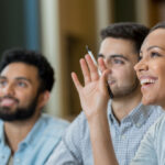 Three individuals smiling and waving