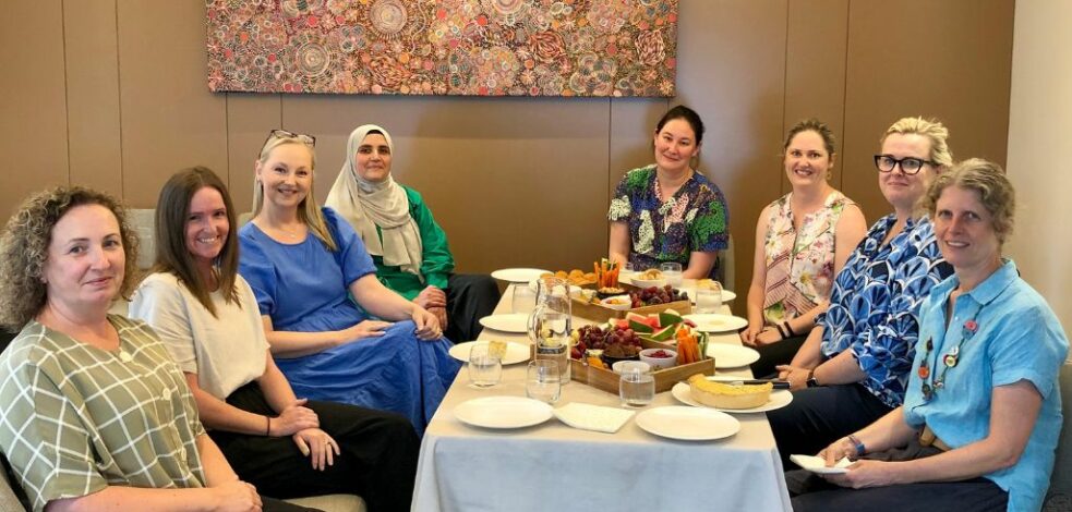 Eight practitioners sit around a restaurant table smiling for the camera.