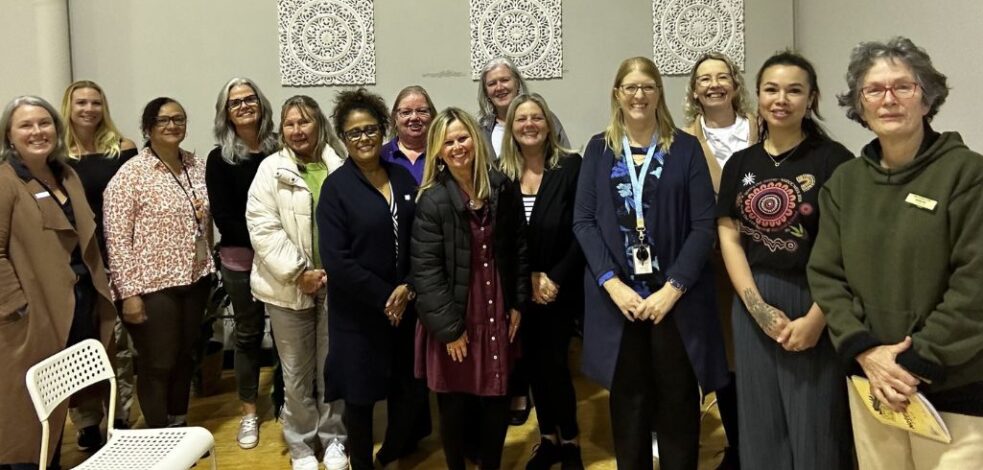 A group of practitioners stand together for a photo indoors after their network meeting.