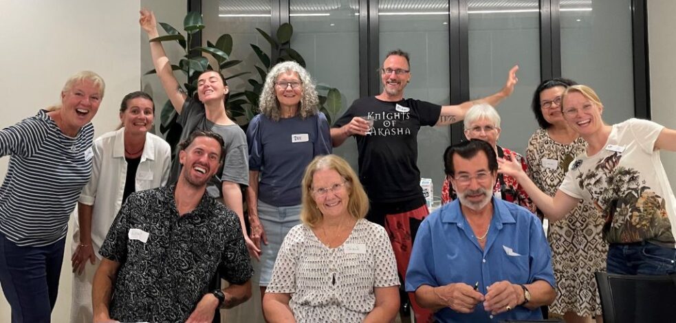 A group of practitioners stand and sit together to pose happily for a photo.
