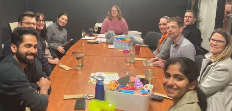 A group of practitioner sit around a meeting room table with sensory toys.